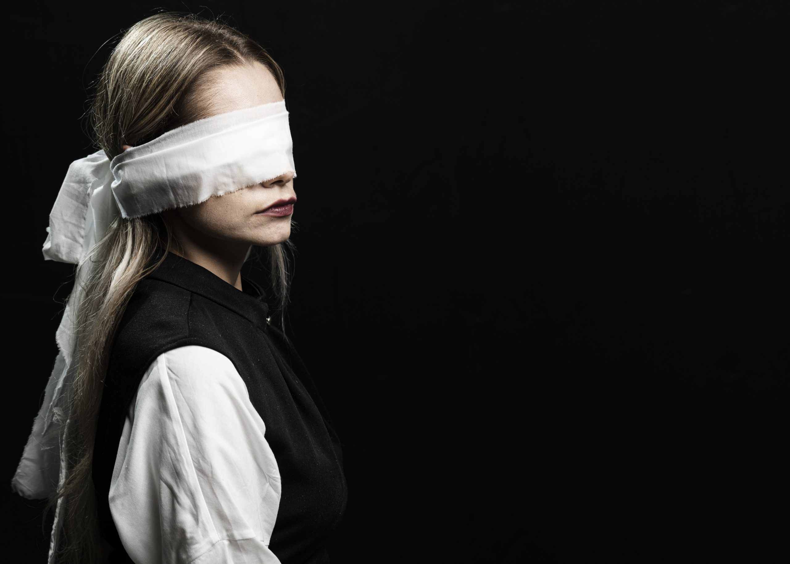 A close-up image of a young girl wearing a blindfold, symbolizing vulnerability, exploitation, and the need to protect against online abuse and threats.